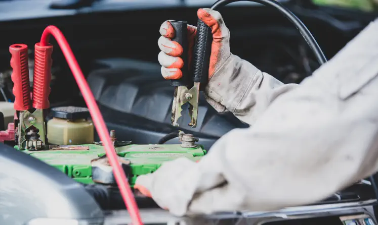Técnico conectando los cables de arranque a la batería de un carro